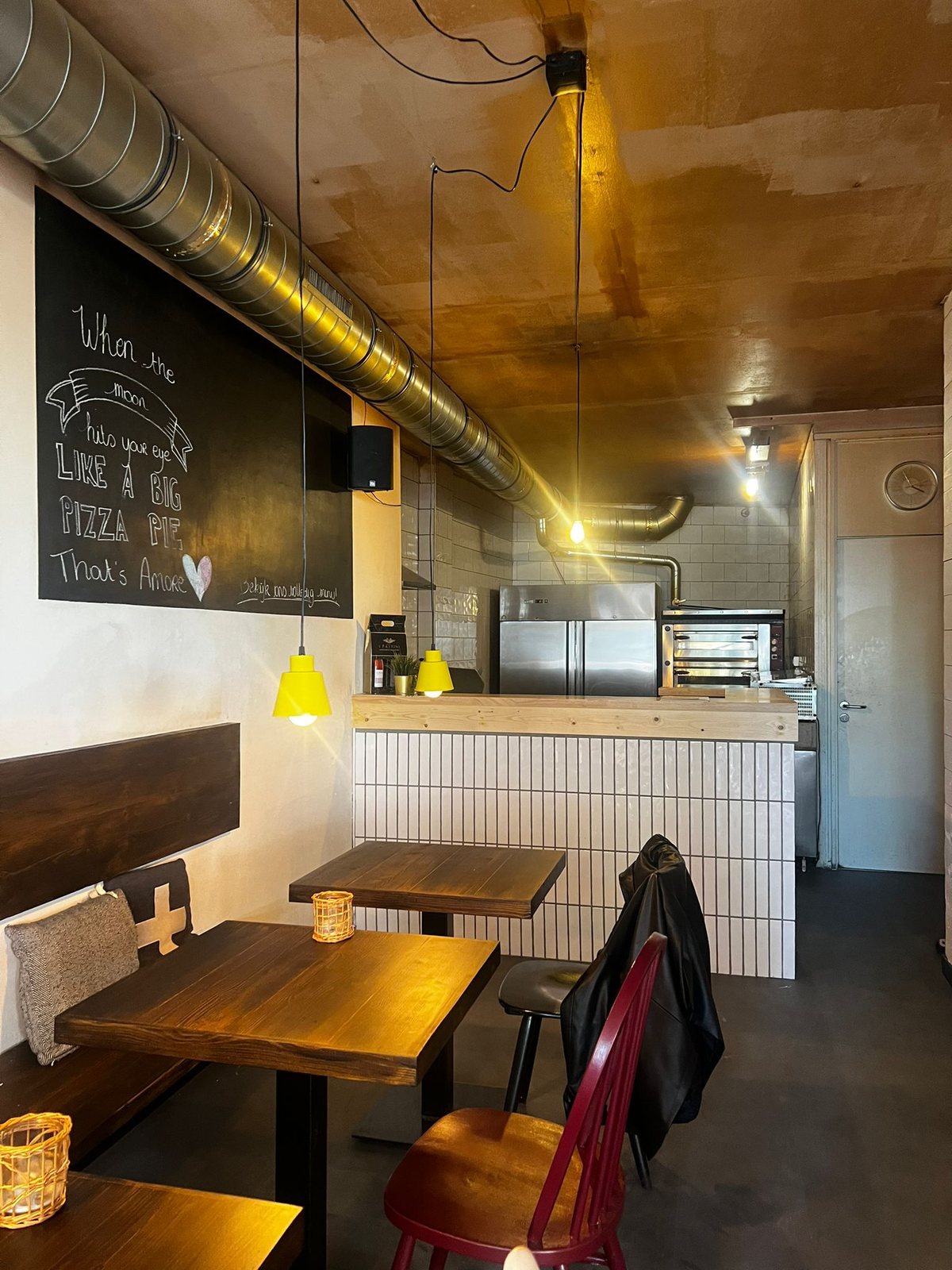 Krijtbord met de tekst 'When the moon hits your eye like a big pizza pie, That's Amore' naast de pizza-oven